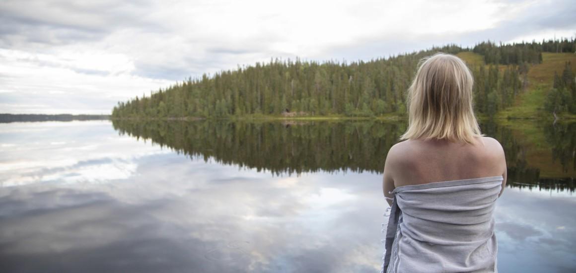 Nainen tyynen järven rannalla