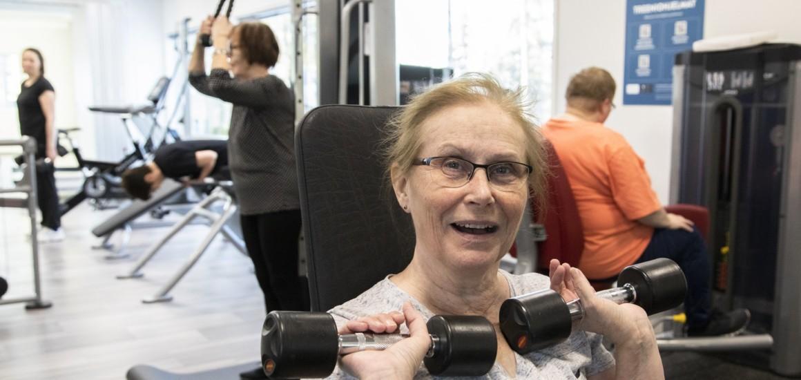 Nainen nostaa painoja Posion Taikasalilla