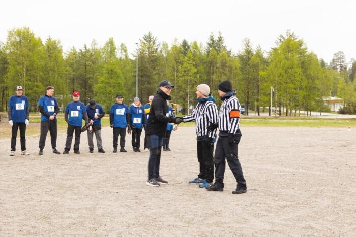 Kunnanjohtaja pitelee pokaalia ja kättelee peräpallopelin tuomaria