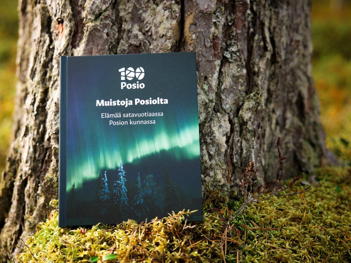 Muistoja Posiolta -kirja nojaa puuhun, puussa paksu kaarna